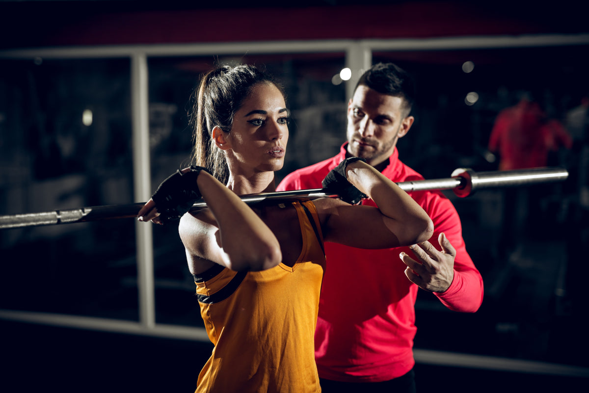 Allenamento con bilanciere e personal trainer in palestra